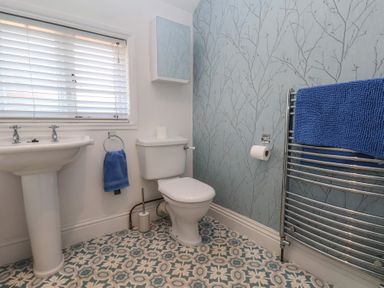 A bathroom with a toilet sink towel radiatior and patterned floor at Trackside Ruswarp