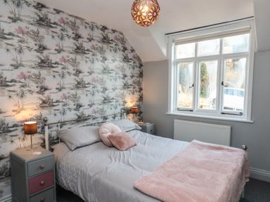 A bedroom with a bed between two bedside tables and a window at Trackside Ruswarp