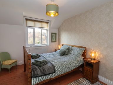 A bedroom with a wooden bed beside nightstands and a window at Trackside in Ruswarp
