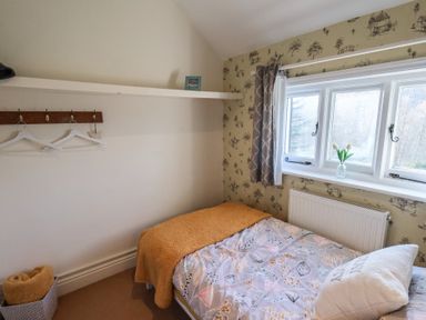 A small bedroom with a single bed under a window and hangers on the wall at Trackside in Ruswarp