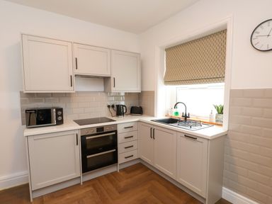 A kitchen with a microwave, oven, and sink at Flat 1 in Rhos-On-Sea
