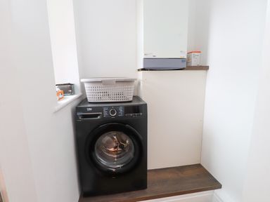 A laundry room with a washing machine and a shelf at Flat 1 Rhos-On-Sea