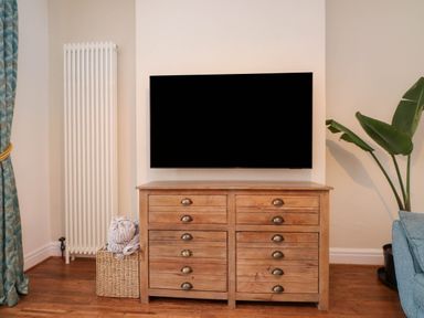 A living room with a television on a chest of drawers at Flat 1 in Rhos-On-Sea