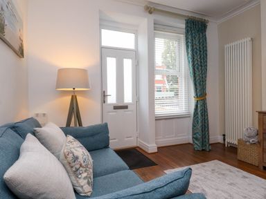A living room with a sofa and door at Flat 1 Rhos-On-Sea