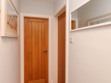 A hallway with wooden doors and a mirror at Flat 1 Rhos-On-Sea