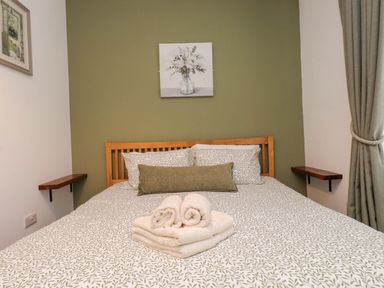 A bedroom with a bed and towels arranged at Flat 1 in Rhos-On-Sea