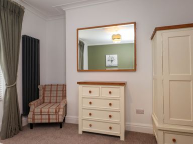 A bedroom with a chair and chest of drawers at Flat 1 Rhos-On-Sea