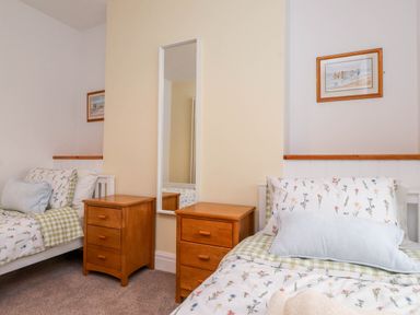 A bedroom with two beds and a mirror at Flat 1 Rhos-On-Sea
