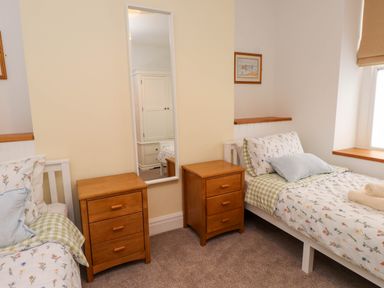 A bedroom with two beds and a mirror at Flat 1 Rhos-On-Sea
