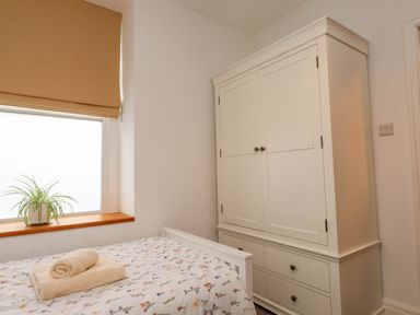 A bedroom with a bed and wardrobe at Flat 1 Rhos-On-Sea