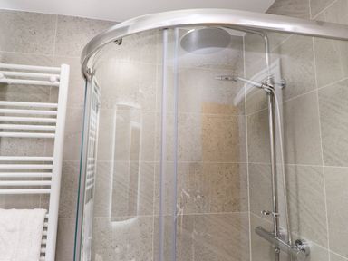 A shower with glass door and towel rack at Flat 1 in Rhos-On-Sea