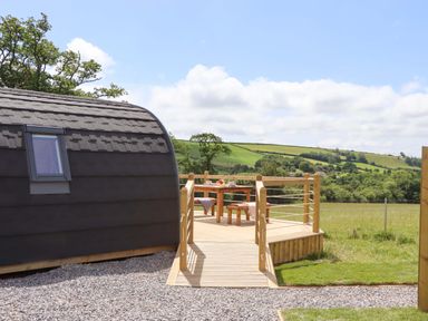 A cabin with a deck and table at Under Oak Pod in Totnes