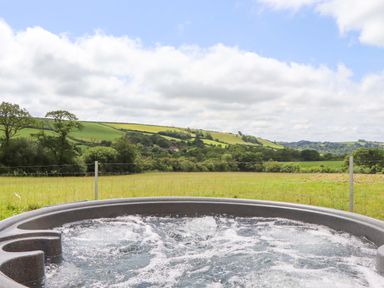 A hot tub with a view of hills and fields at Under Oak Pod in Totnes