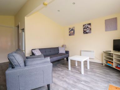 A living room with a sofa, coffee table, and TV at H2 Atlantic Bay Holiday Park in Padstow