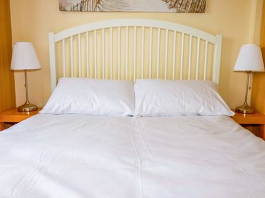 A bed with pillows and lamps at H2 Atlantic Bay Holiday Park in Padstow