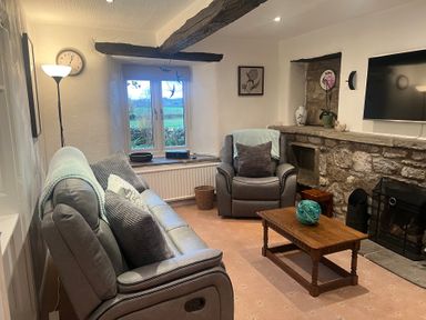 A living room with a sofa, armchair, and fireplace at The Old Farmhouse at Brackenthwaite Farm Yealand Redmayne near Arnside