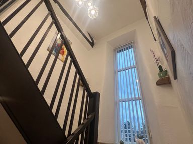A staircase with a light fixture and a window at The Old Farmhouse at Brackenthwaite Farm in Yealand Redmayne near Arnside