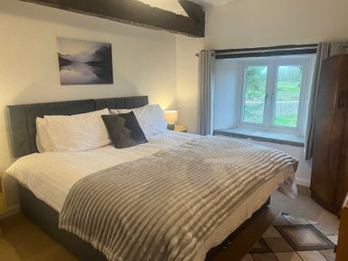 A bedroom with a bed and window at The Old Farmhouse at Brackenthwaite Farm Yealand Redmayne near Arnside