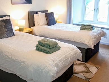A bedroom with twin beds and towels at The Old Farmhouse at Brackenthwaite Farm Yealand Redmayne near Arnside