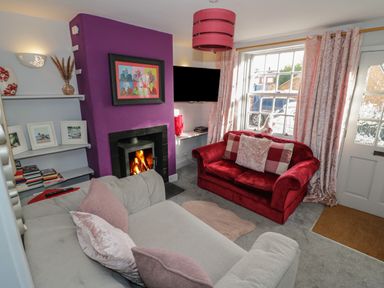 A living room with a red sofa and a white sofa near a fireplace with a purple wall at Cherry Blossom Cottage in Stratford-Upon-Avon