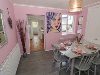 A dining room with a set table and a painting on the wall at Cherry Blossom Cottage in Stratford-Upon-Avon