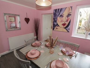 Dining room with pink walls and a table set for six with pink dishes at Cherry Blossom Cottage in Stratford-Upon-Avon