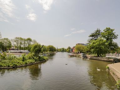 A river with boats and ducks surrounded by trees and a walking path at Cherry Blossom Cottage in Stratford-Upon-Avon