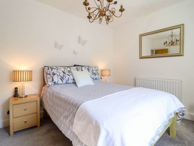 A bedroom with a double bed two bedside tables and lamps a wall mirror and a chandelier at Dola in Pentre Du near Betws Y Coed