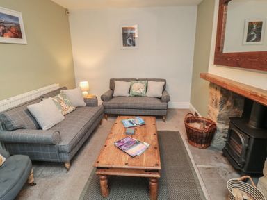 A living room with two gray sofas a wooden coffee table and a wood burning stove at Providence Cottage in Ugglebarnby near Sleights