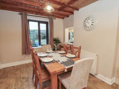 A dining room with wooden table set with plates and glasses under a wooden ceiling at Providence Cottage in Ugglebarnby near Sleights