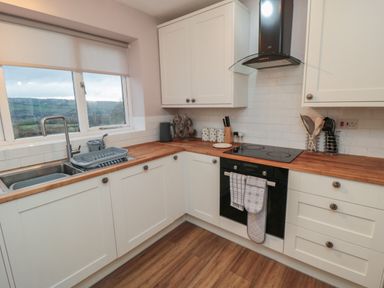 A kitchen with white cabinets wooden countertops a stove oven sink and window at Providence Cottage in Ugglebarnby near Sleights