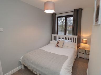 A bedroom with a bed pillow lamp and a window with curtains at Providence Cottage in Ugglebarnby near Sleights