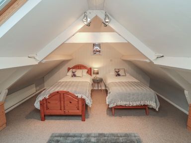 An attic bedroom with two single beds a bedside table with lamp and a small picture on the wall at Providence Cottage in Ugglebarnby near Sleights