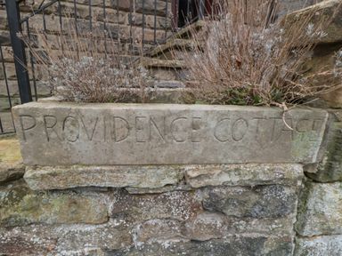 Stone planter with dried plants and the inscription PROVIDENCE COTTAGE on a stone wall at Providence Cottage in Ugglebarnby near Sleights