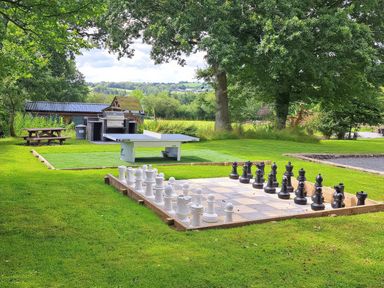 An outdoor area with a large chess set a ping pong table picnic bench and barbecue on grass at Teifi Cottage in Cardigan Near Cenarth