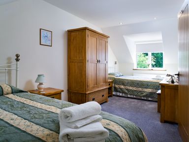 A bedroom with two single beds a wooden wardrobe a wooden desk and a window with a view at Cych Cottage Cardigan Near Cenarth