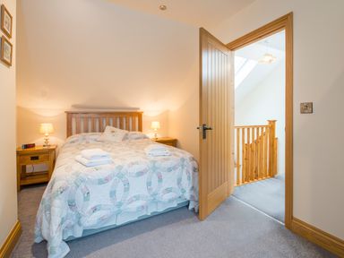 A bedroom with a wooden bed and two bedside tables with lamps at Cych Cottage Cardigan Near Cenarth