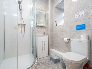 A bathroom with a shower, vanity, toilet, and a small stool at Towy Cottage in Cardigan Near Cenarth