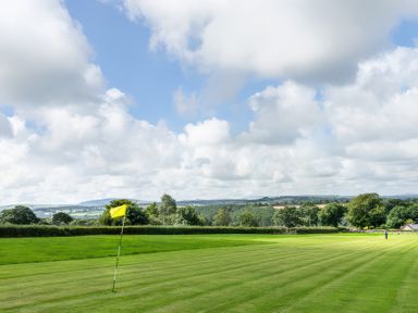 A golf course with yellow flags on the green and trees in the background at Towy Cottage Cardigan Near Cenarth