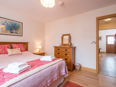 A bedroom with a bed with towels on it a wooden dresser and a door leading to a hallway at Gwaun Cottage Cardigan Near Cenarth