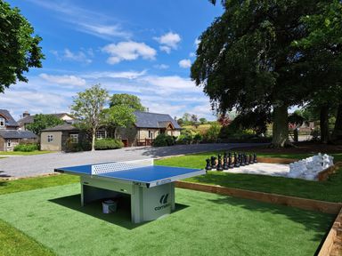 An outdoor area with a ping pong table and a large chessboard with oversized chess pieces near stone buildings at Gwaun Cottage in Cardigan Near Cenarth