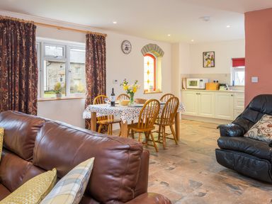 An open living room and kitchen with a dining table set with chairs and flowers at Cothi Cottage Cardigan Near Cenarth