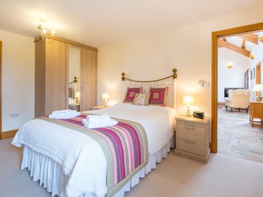 A bedroom with a double bed bedside tables lamps and a wardrobe at Hirwaun Cottage in Cardigan Near Cenarth