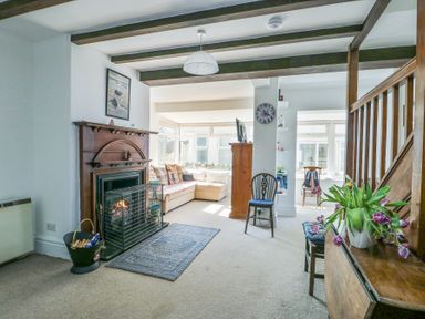 A living room with a wooden fireplace a carpet and a sofa near windows at The Harbour in Rhosneigr