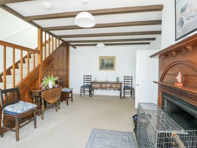 A room with wooden stairs two chairs a table and a fireplace at The Harbour in Rhosneigr