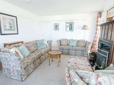 A living room with patterned sofas a wooden coffee table a fireplace and framed pictures on the wall at The Harbour in Rhosneigr