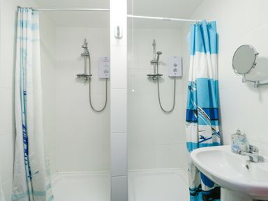 A bathroom with two separate shower stalls and a sink with a mirror at The Harbour in Rhosneigr