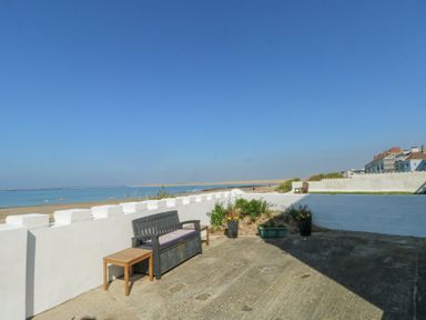 A patio with benches tables plants and a sea view at The Harbour in Rhosneigr