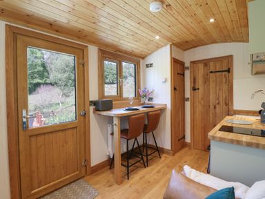 A small kitchen area with wooden ceiling wooden door and windows and a breakfast bar with two chairs at Celyn in Bontddu near Dolgellau