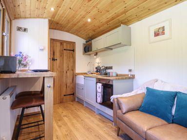 A kitchen area with wooden countertops and a brown leather sofa with blue cushions at Celyn in Bontddu near Dolgellau